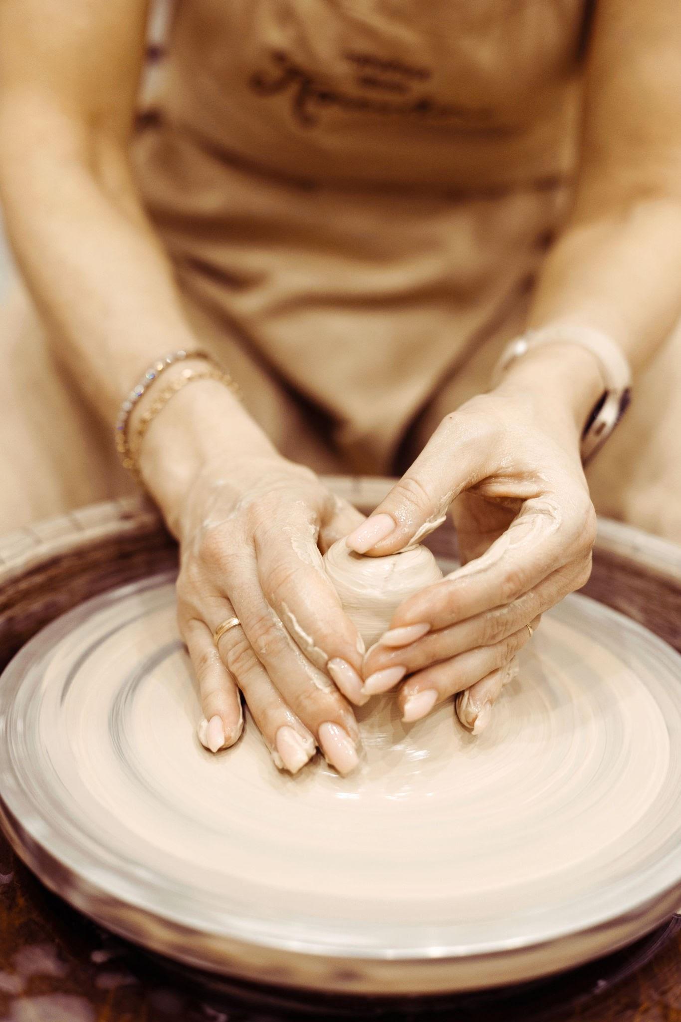 Hands centring wet clay on a potter's wheel
