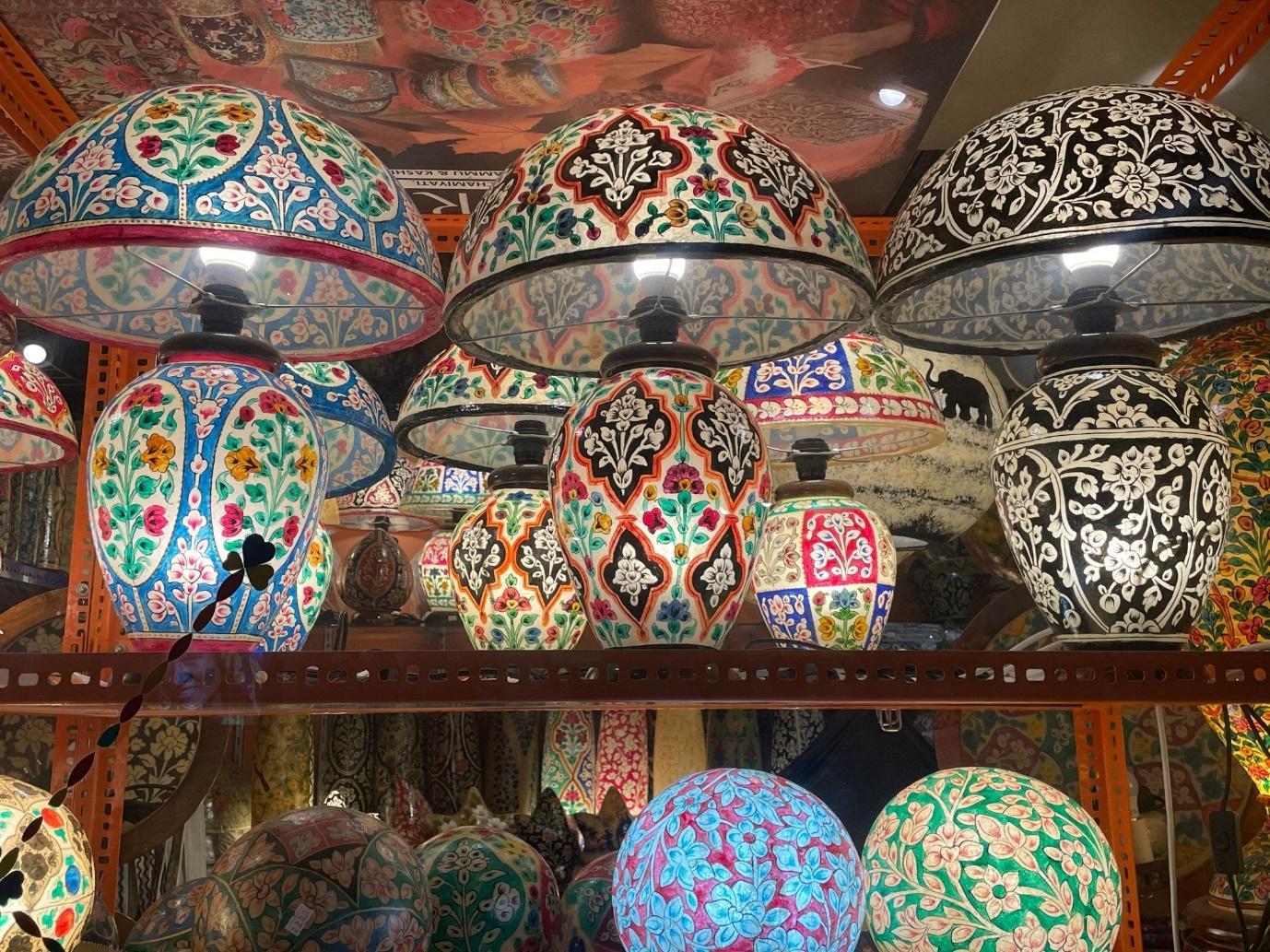 Rows of illuminated naqashi camel-skin lamps in floral and geometric patterns