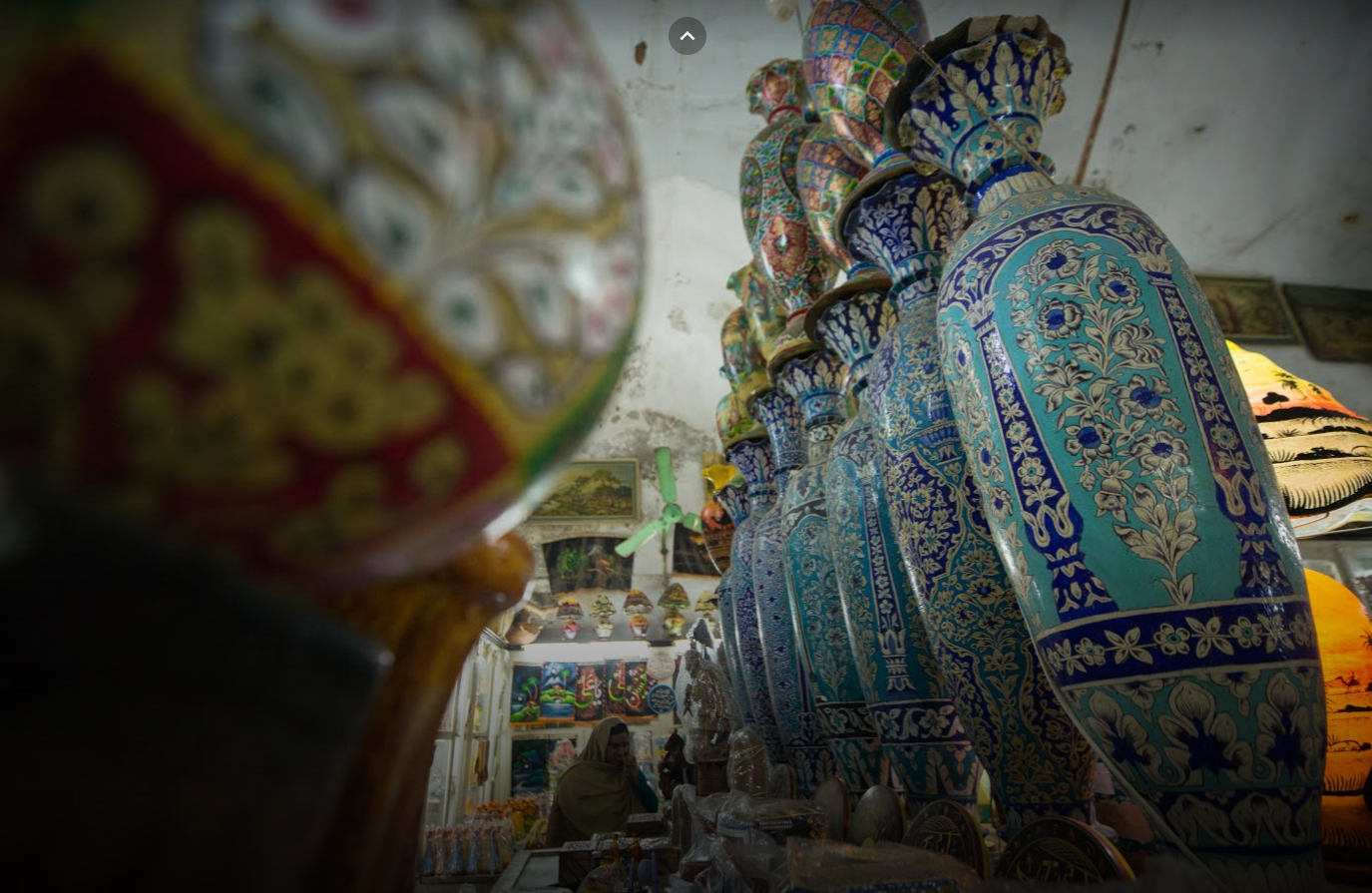A naqashi lampshade framing the vases behind